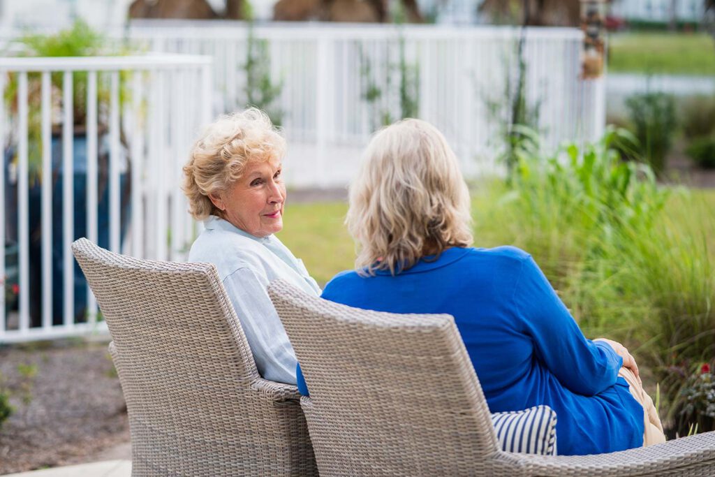 Two senior women seated on patio
